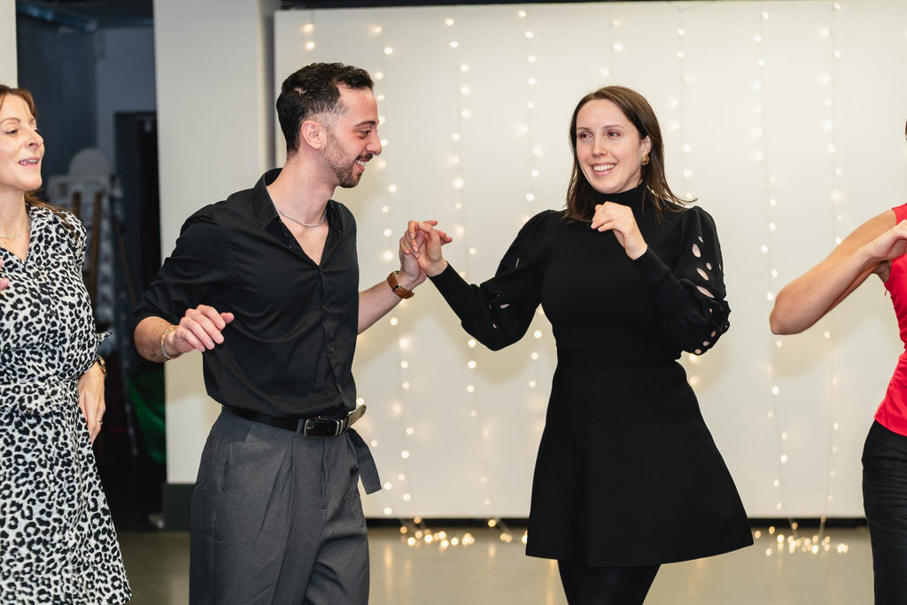 A couple dancing salsa in a Sabroso class, both smiling